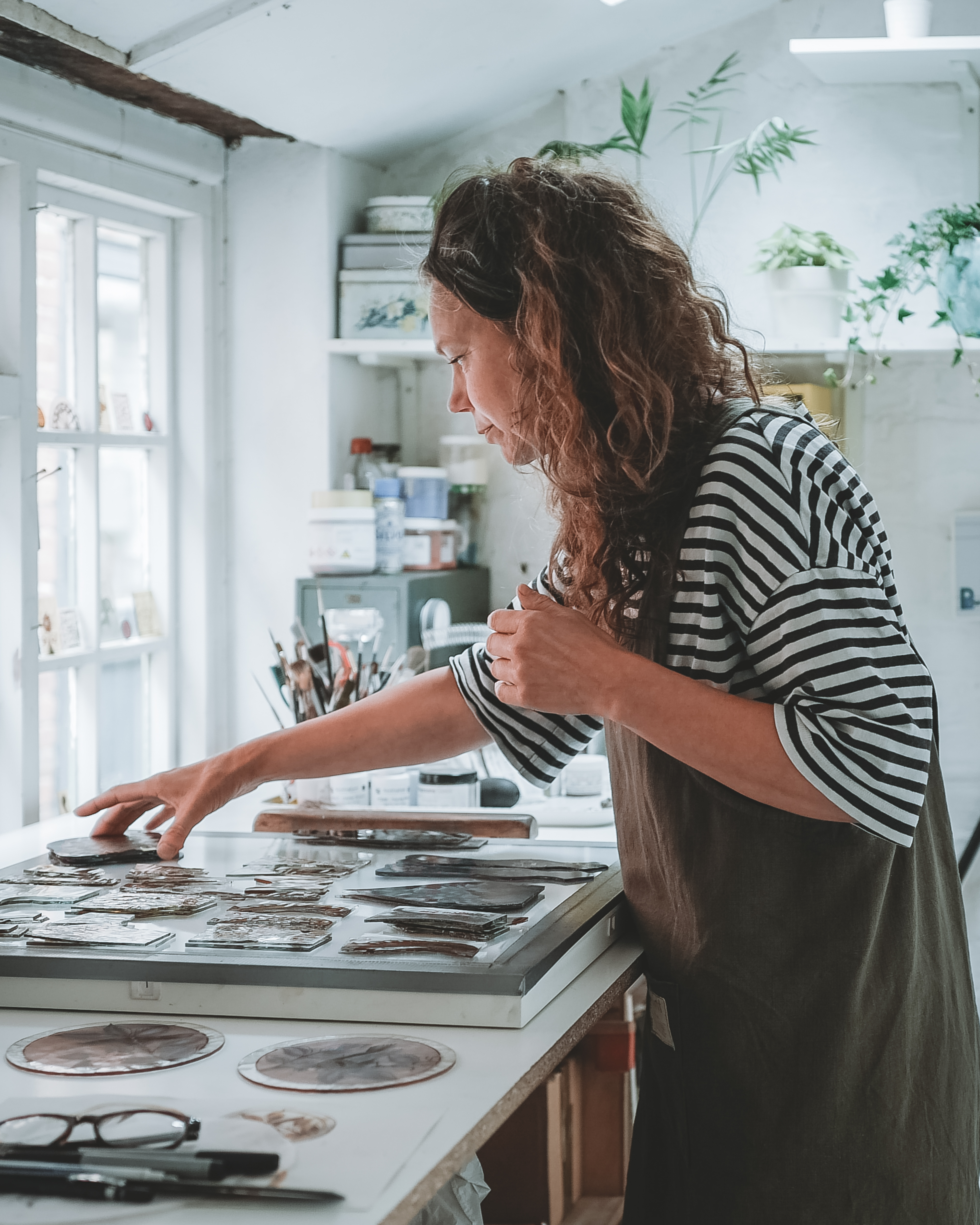 Flora Jamieson working with different stained glass pieces in her studio