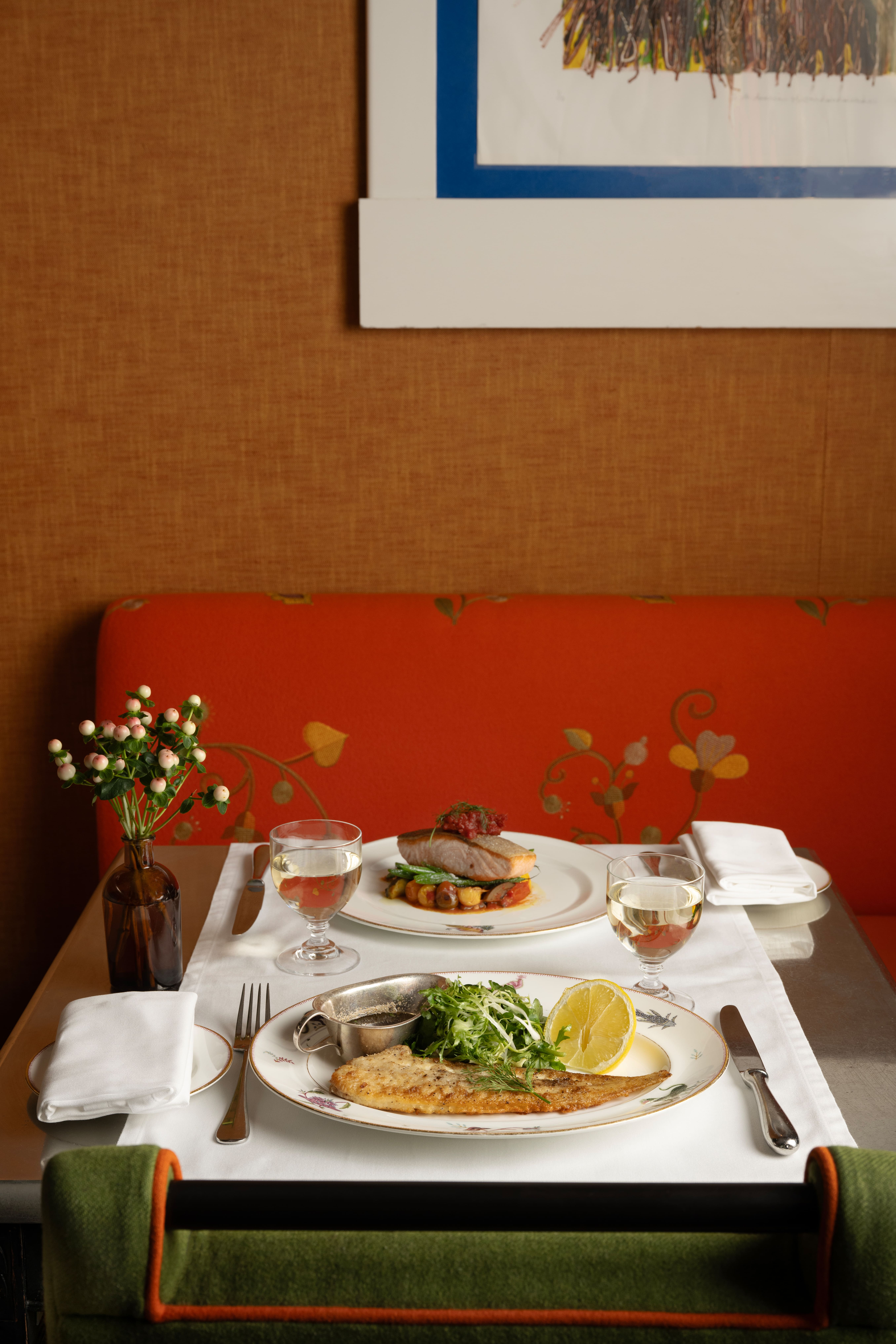A close-up portrait shot of a table set up for dinner at The Crosby Bar: there are dishes of dover sole and salmon