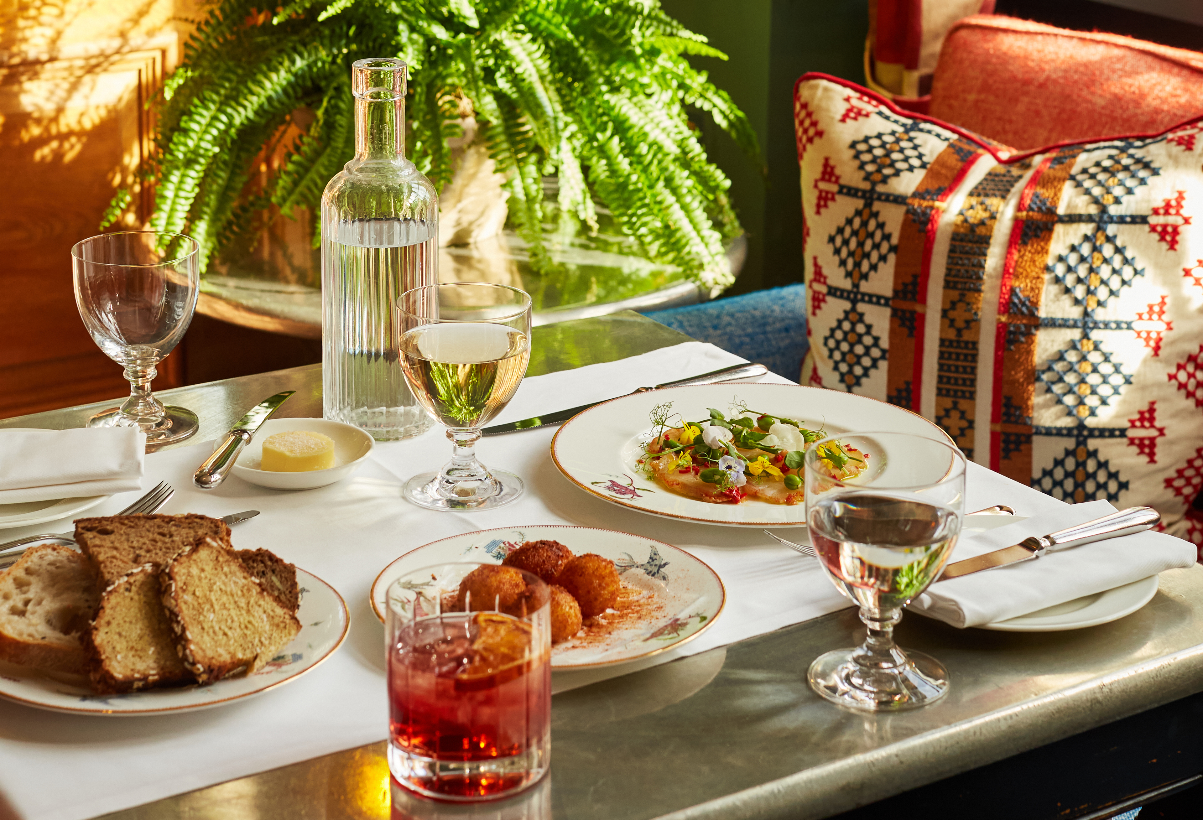 A wide shot of a table at Oscar with starters of bread, arancini and cured cod