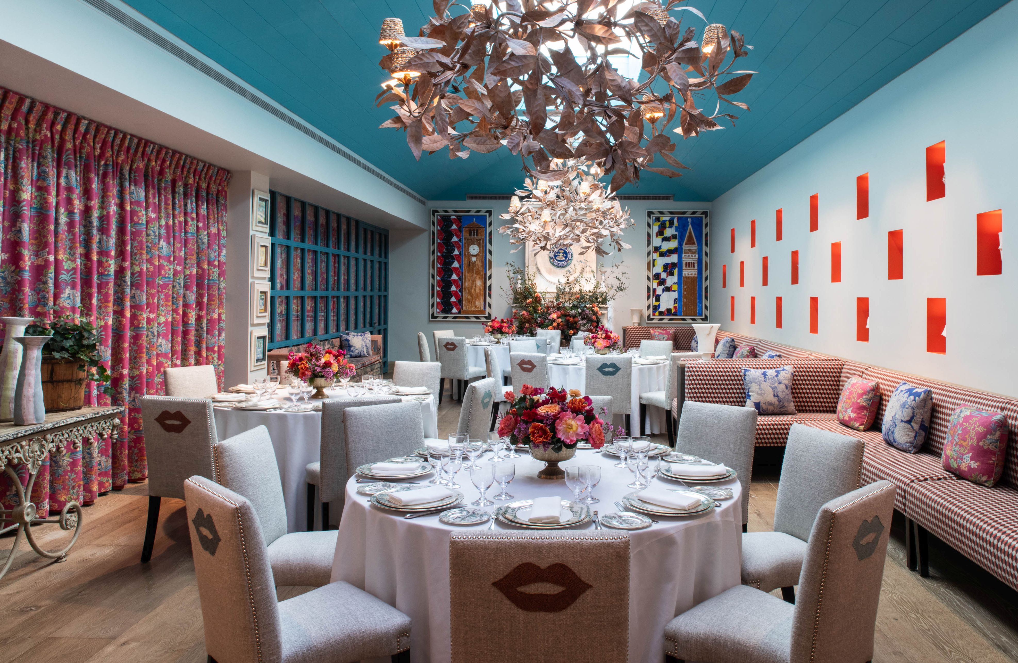 A Round dining tables set-up with dinnerware and glassware showcasing a chandelier and Orangery private events room at Warren Street Hotel