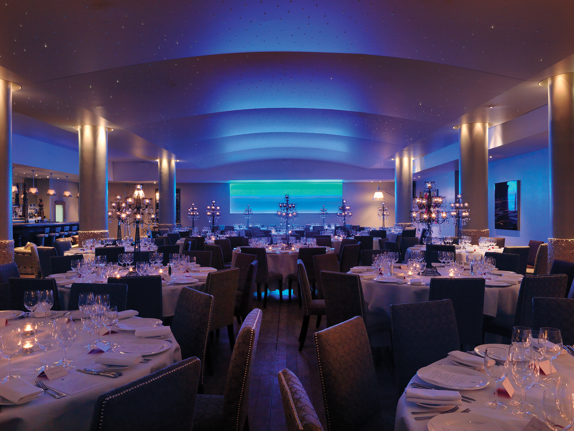 Wide shot of round dining tables in the Swimming pool private events room at Haymarket Hotel