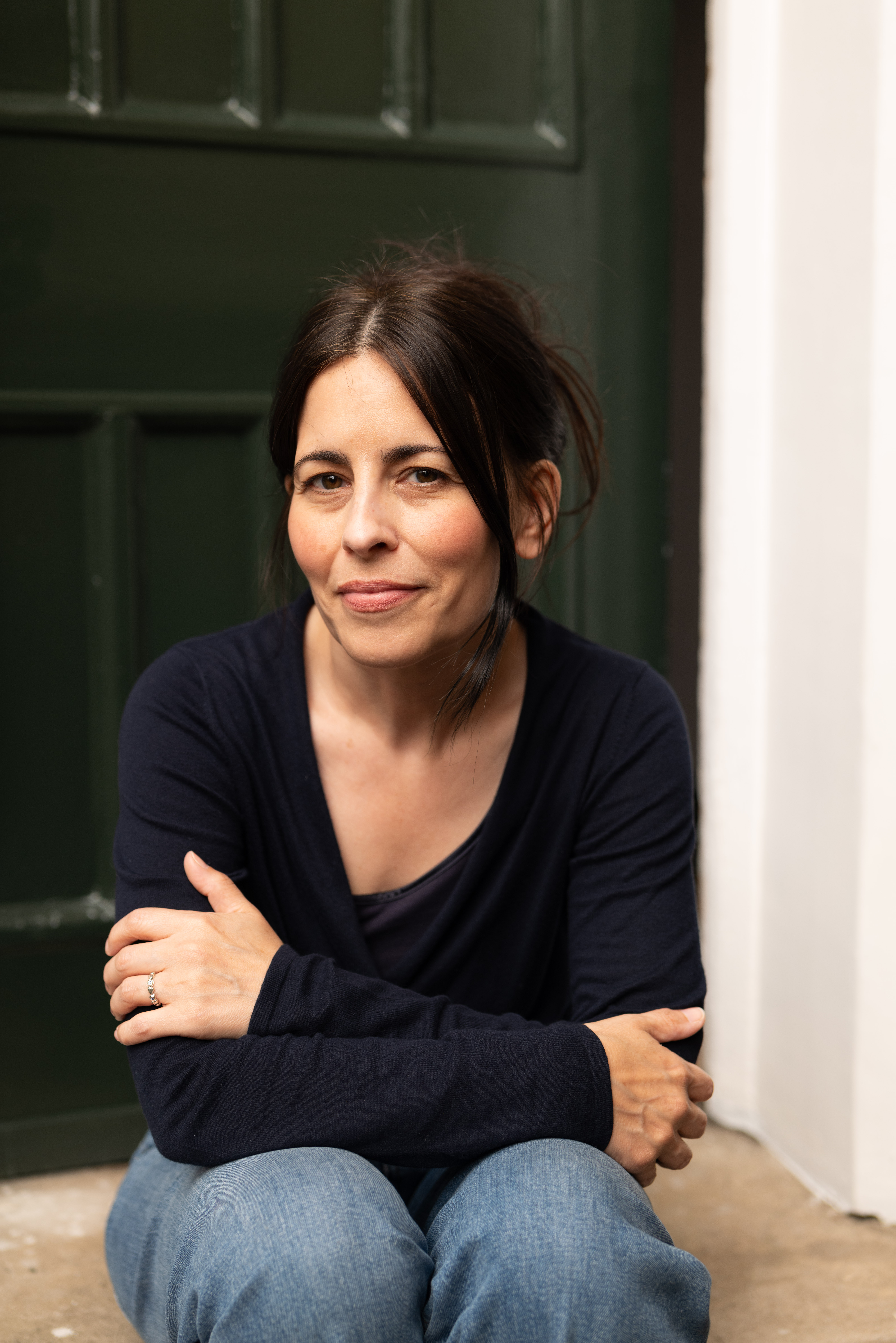 A headshot of author Florence Knapp, she sits on a step outside a front door