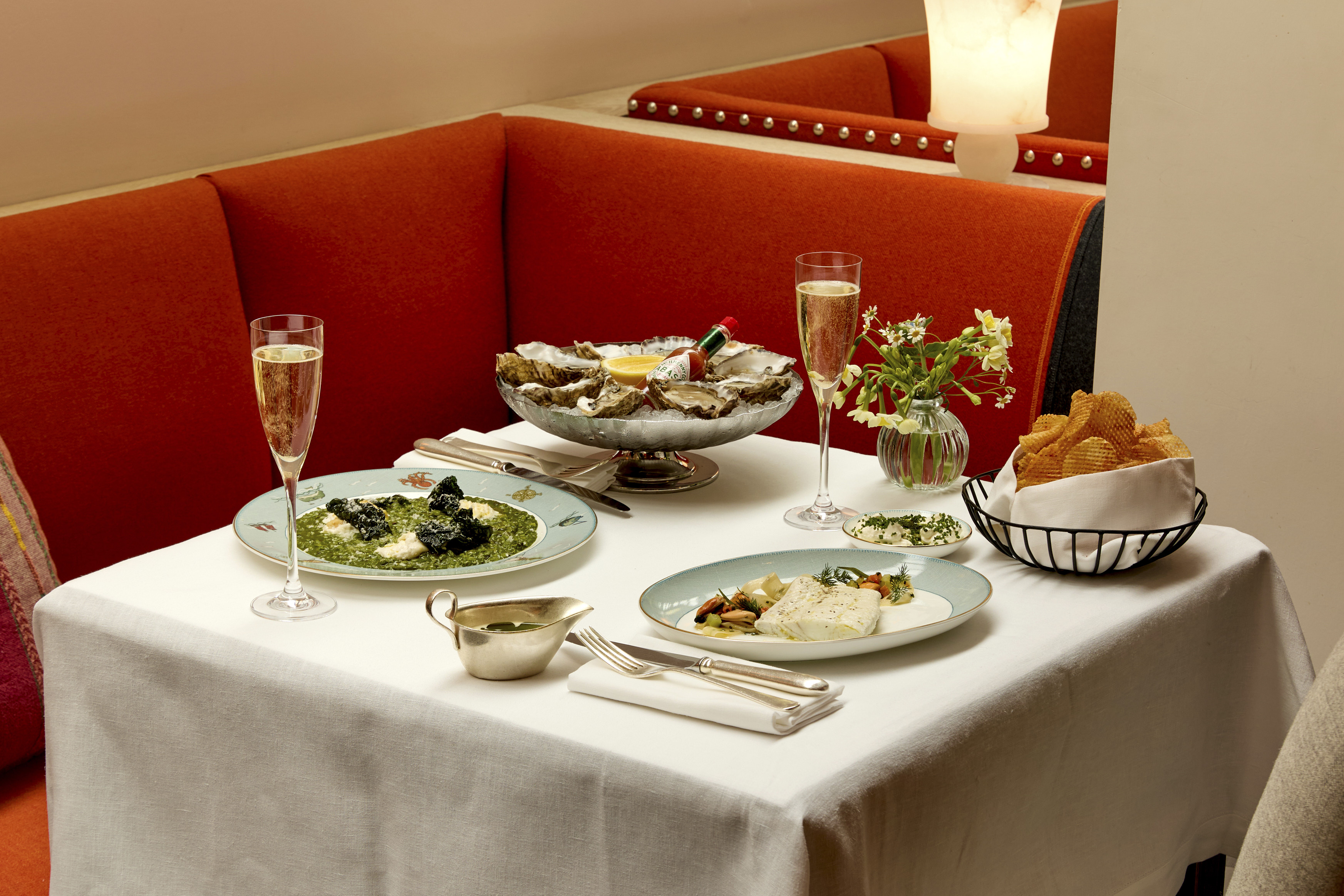Wide shot of oysters, poached brill, chard risotto and game chips in the restaurant at Ham Yard Hotel