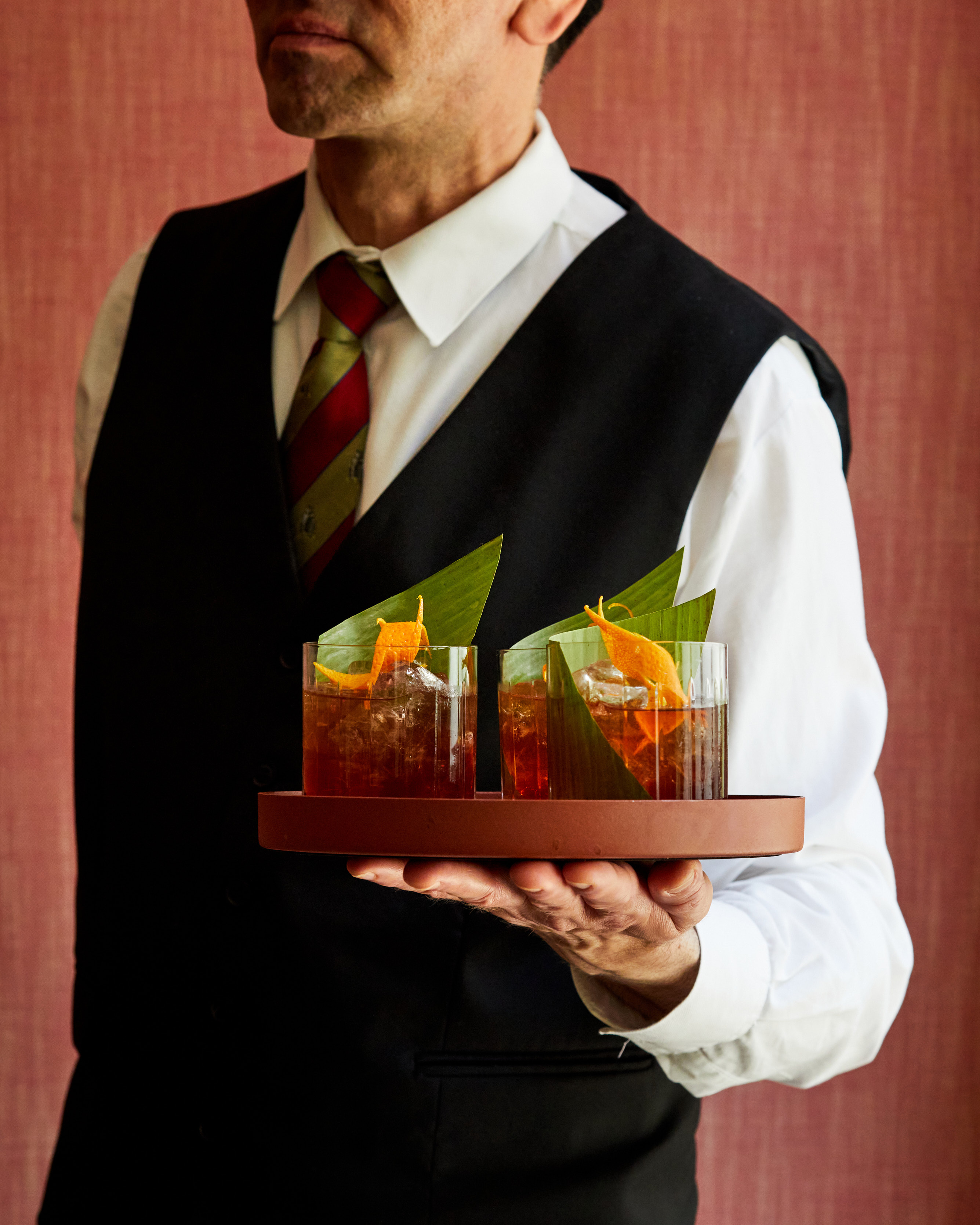 A male member of staff holding a tray of three You take the high road…cocktails at Refuel, The Soho Hotel.