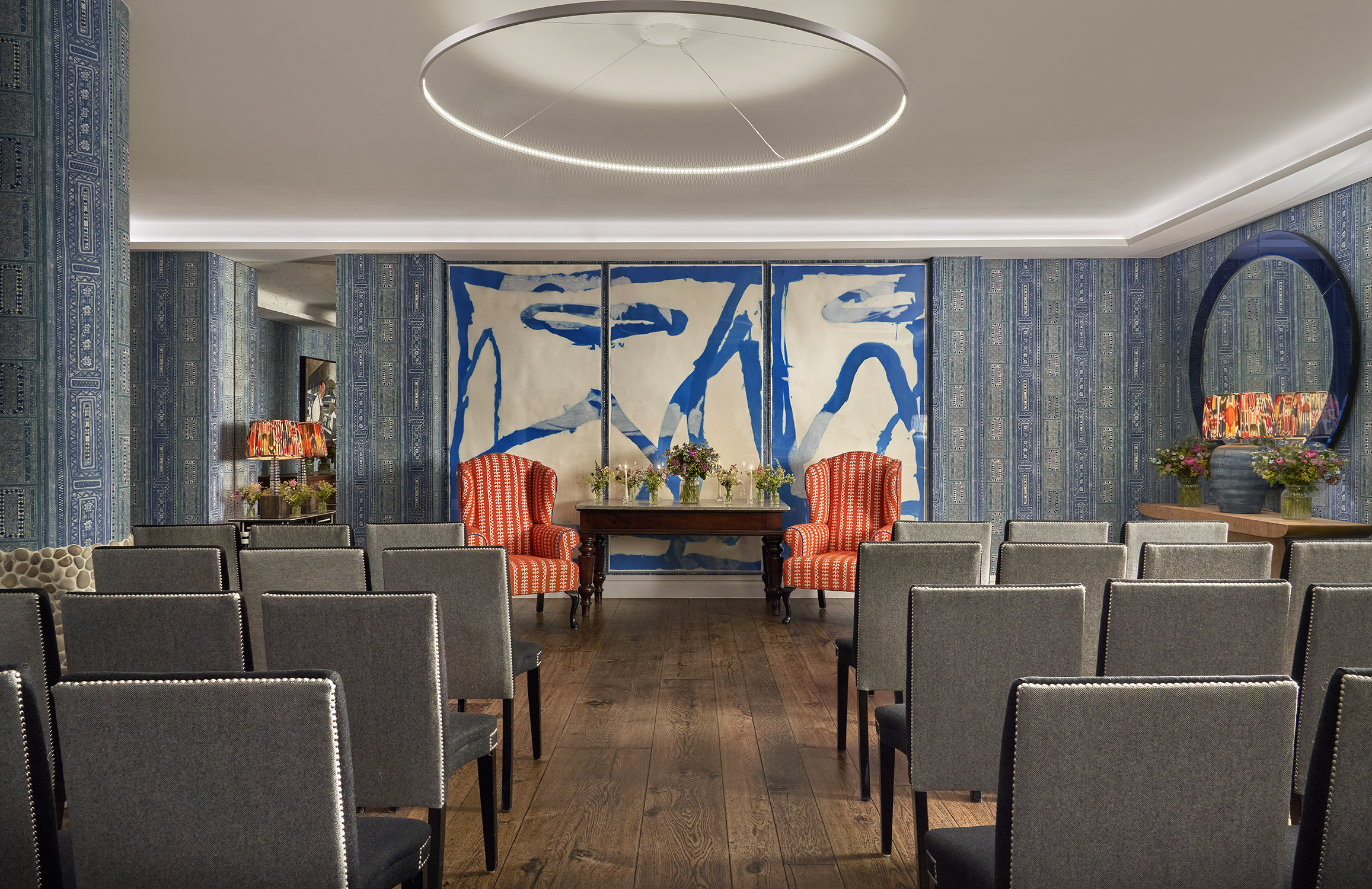 An image of the wedding set in The Indigo Room, a private event room, in The Soho Hotel. With 4 rows of 8 grey chairs across the room, with an aisle down the middle.