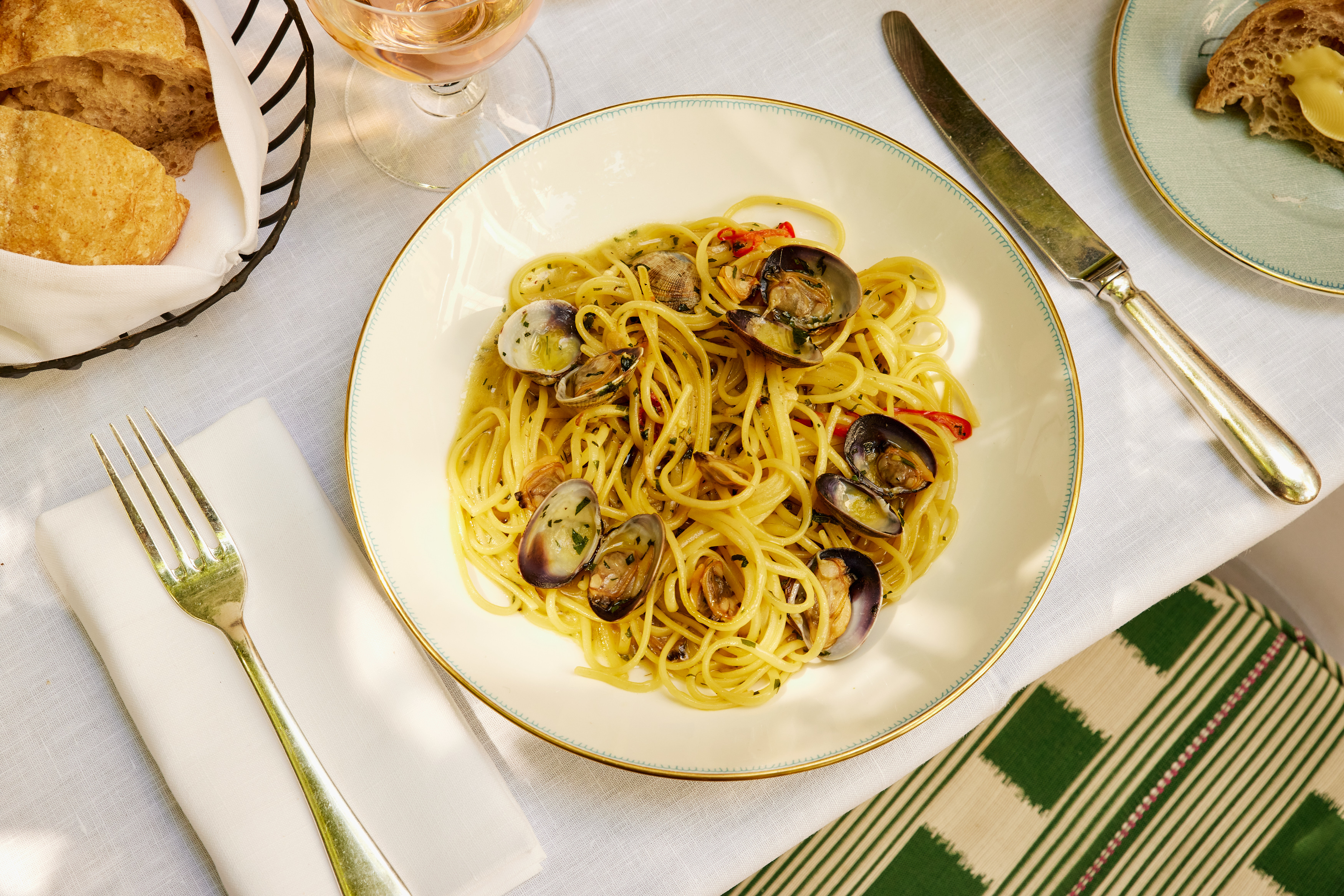 A close-up wide angle shot of the linguine alle vongole, paired with a glass of rose wine outside in the courtyard at Ham Yard Bar & Restaurant
