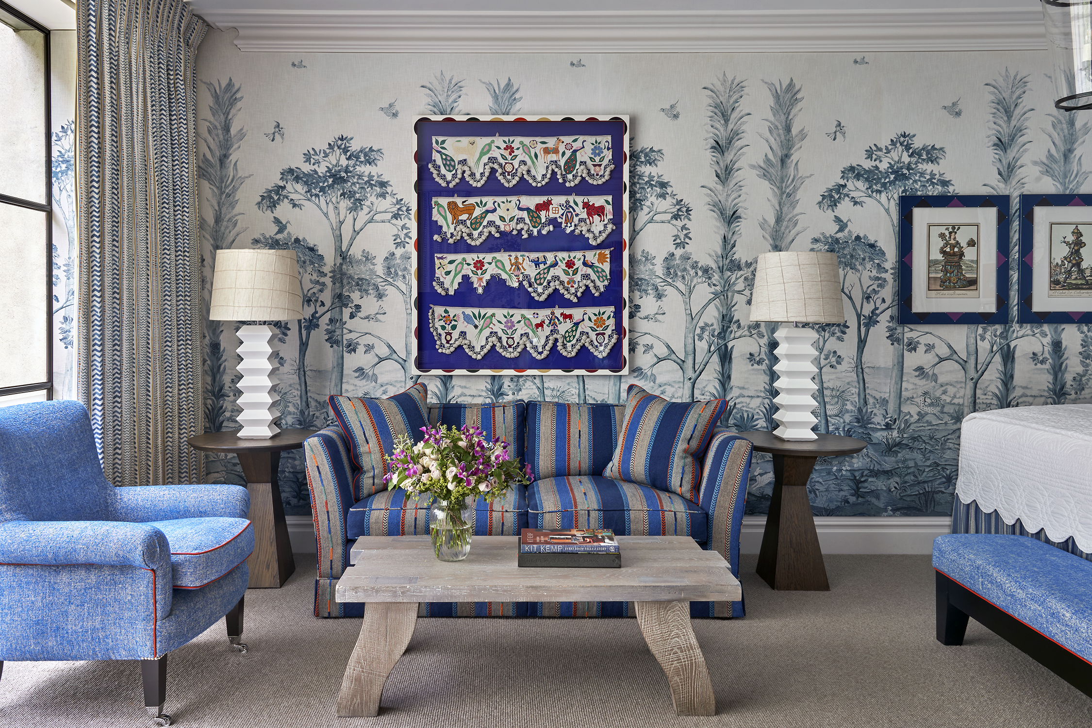 The sitting area of the bedroom in a Deluxe Junior Snug Suite at Ham Yard Hotel, featuring a blue sofa, armchair and coffee table with two small side tables and lamps either side