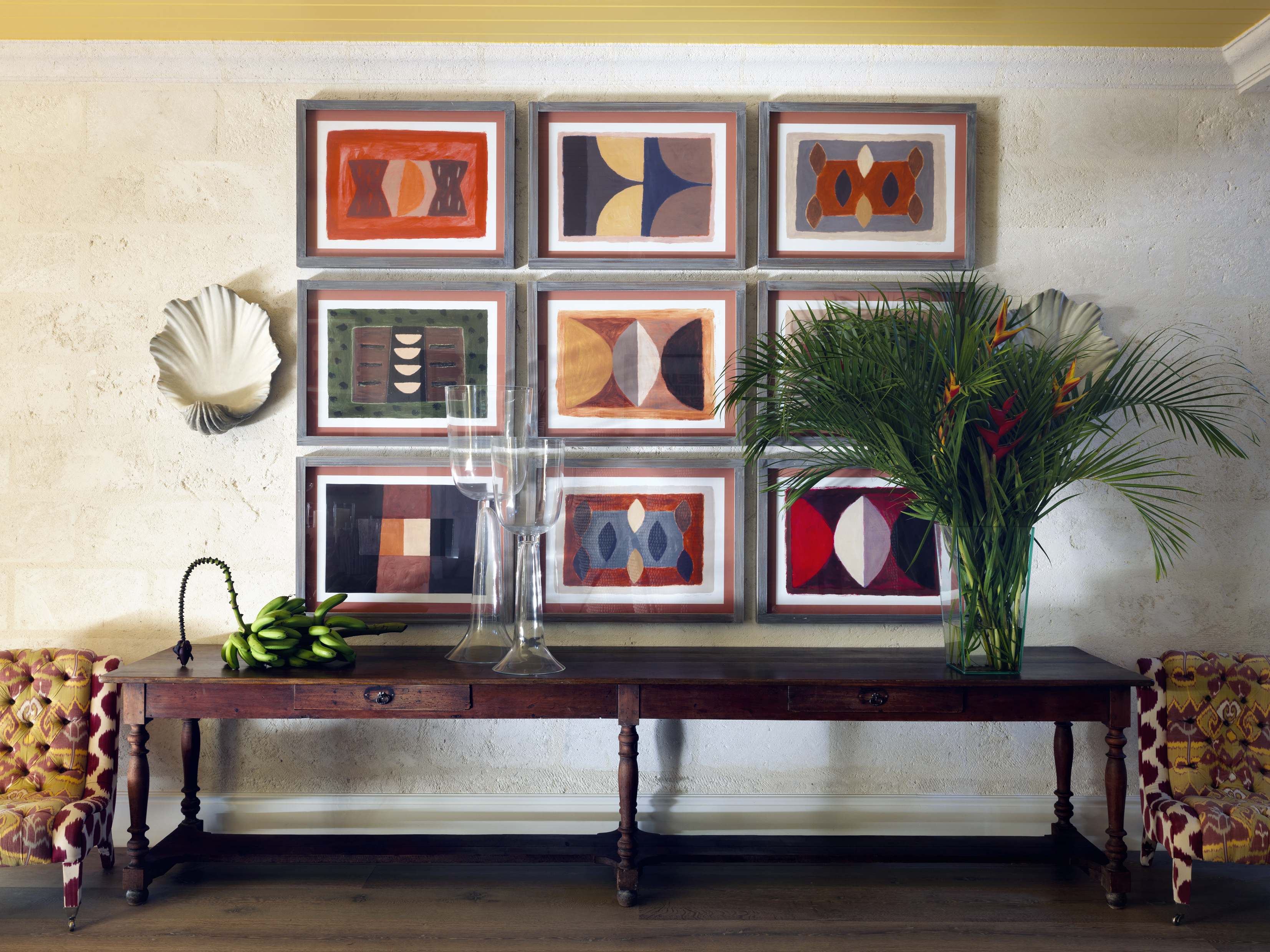 Wide Shot of the Hallway at Rossferry with bunch of banana, a vase of palmtree, and two big glasses ontop a wooden console and some art work.