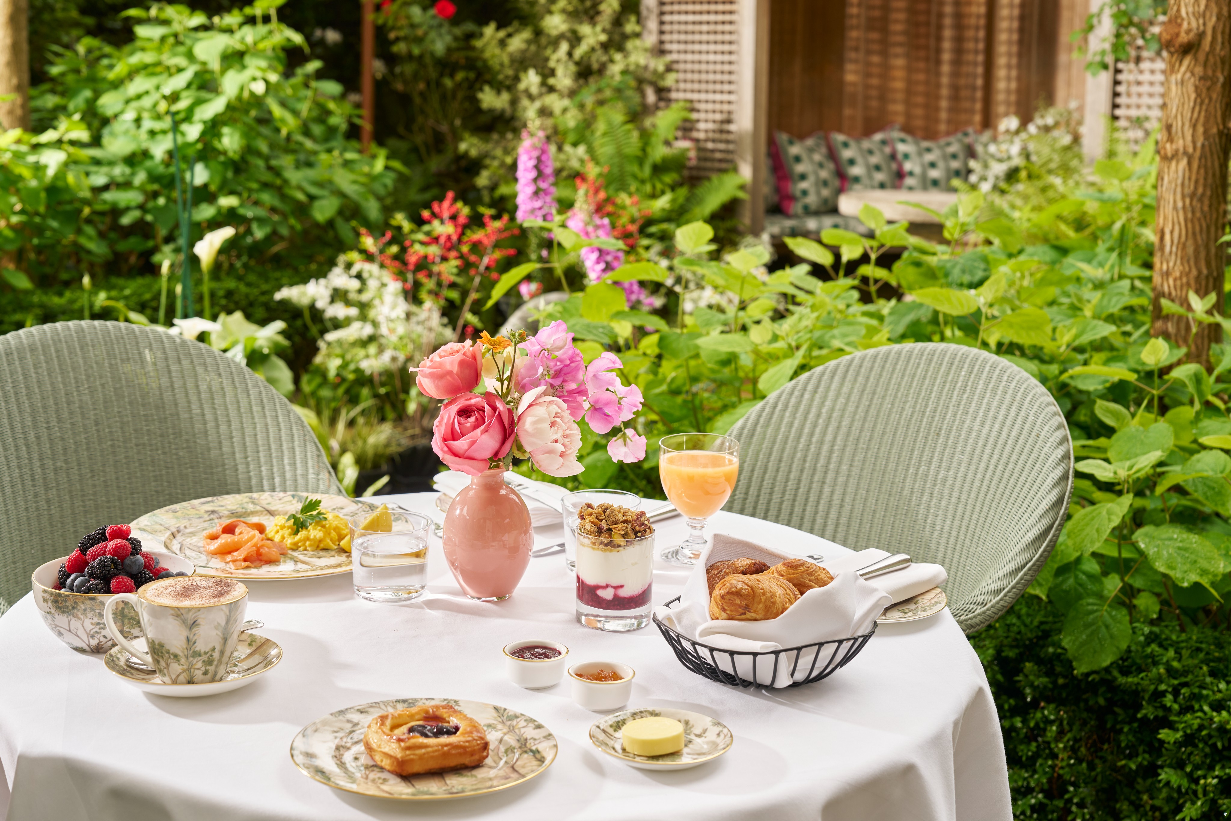 Breakfast in the garden at The Orangery. Table displays a pot of yoghurt and plates of pastries and eggs with smoked salmon shot in the garden