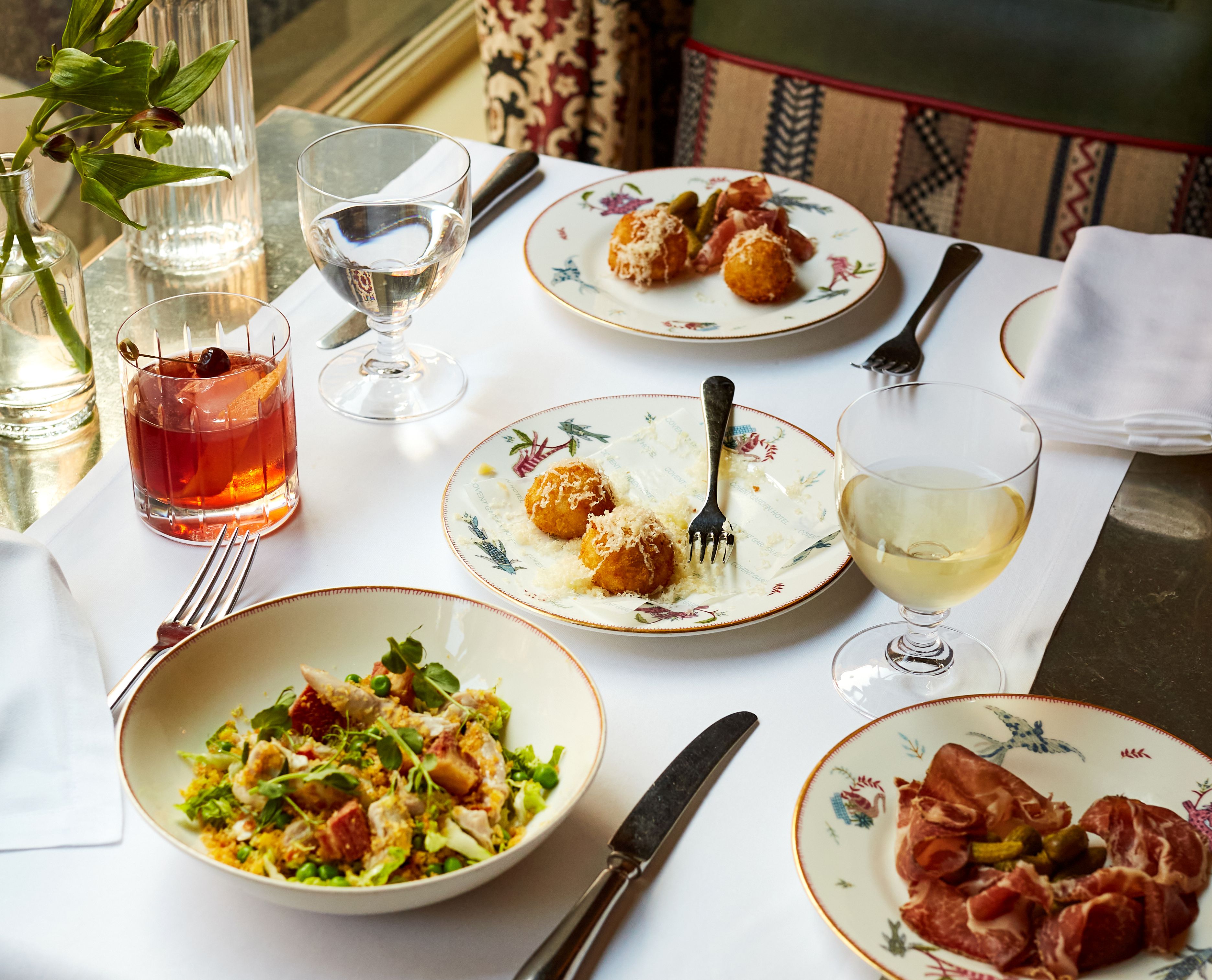 Wide shot of bar food on a table at Brasserie Max. Plates of ham, arancini and salad