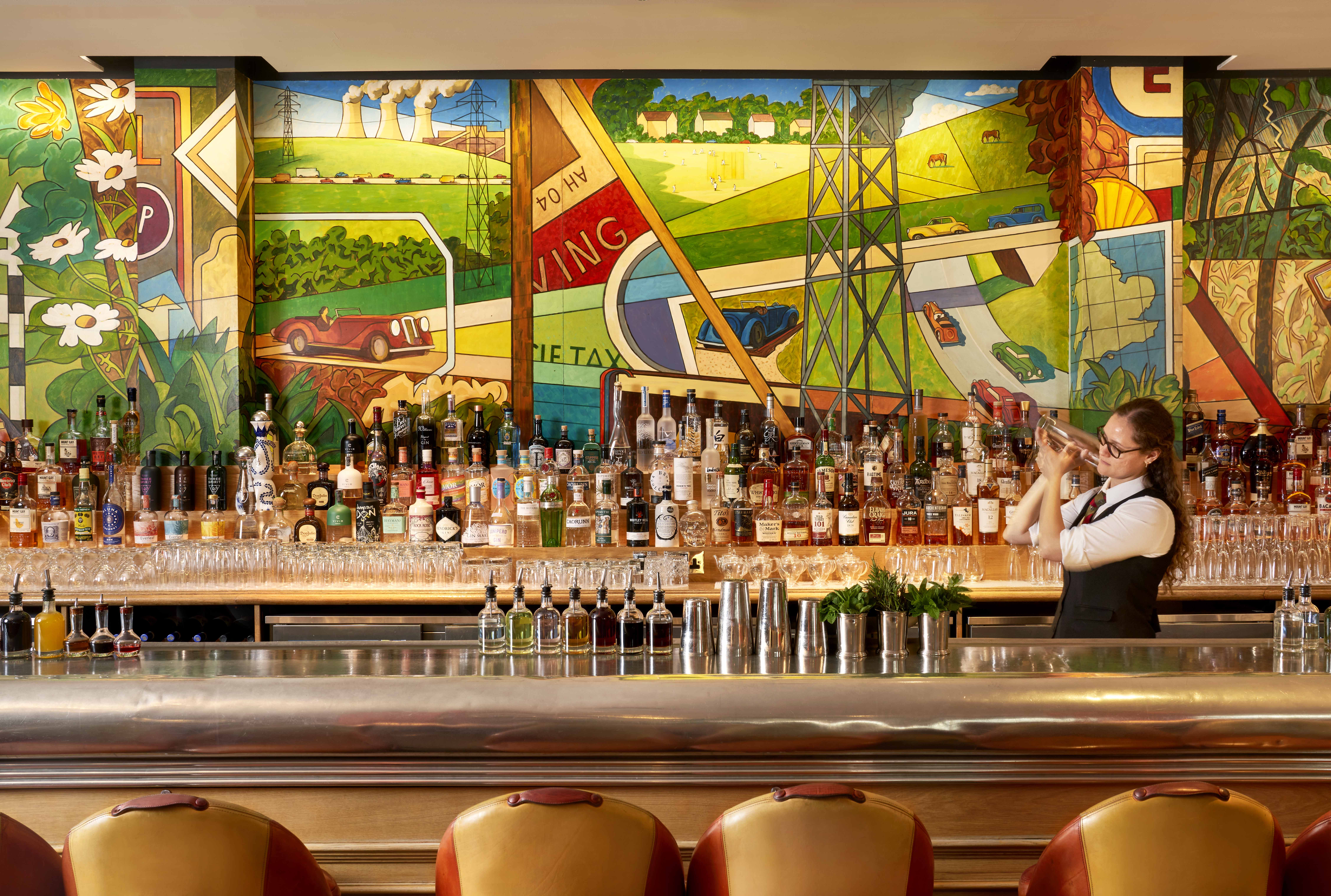 A female bartender shaking a cocktail behind the bar at Refuel Restaurant