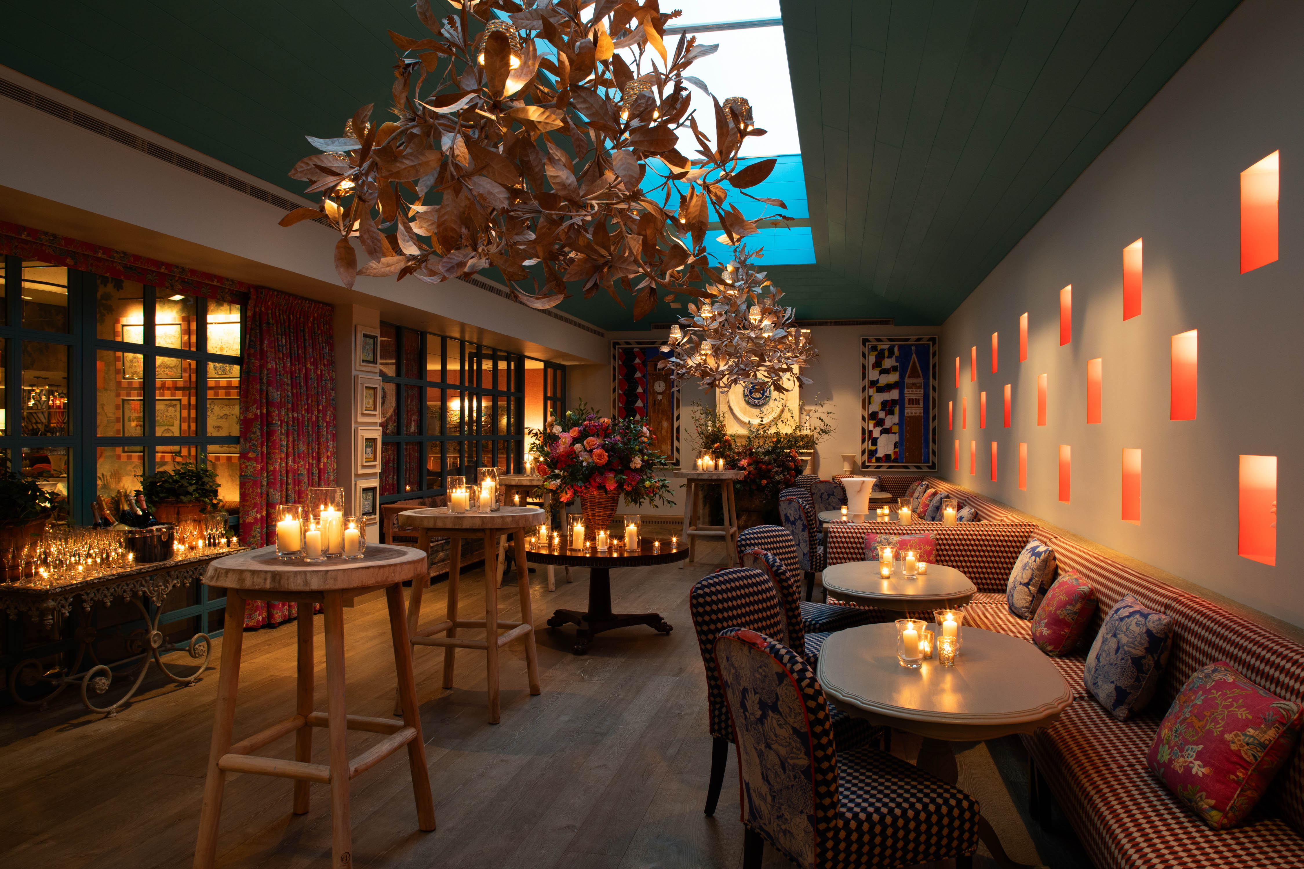 Close shot of a warm candlelight, floral decor, and gold leaf chandeliers at Orangery private events room at Warren Street Hotel