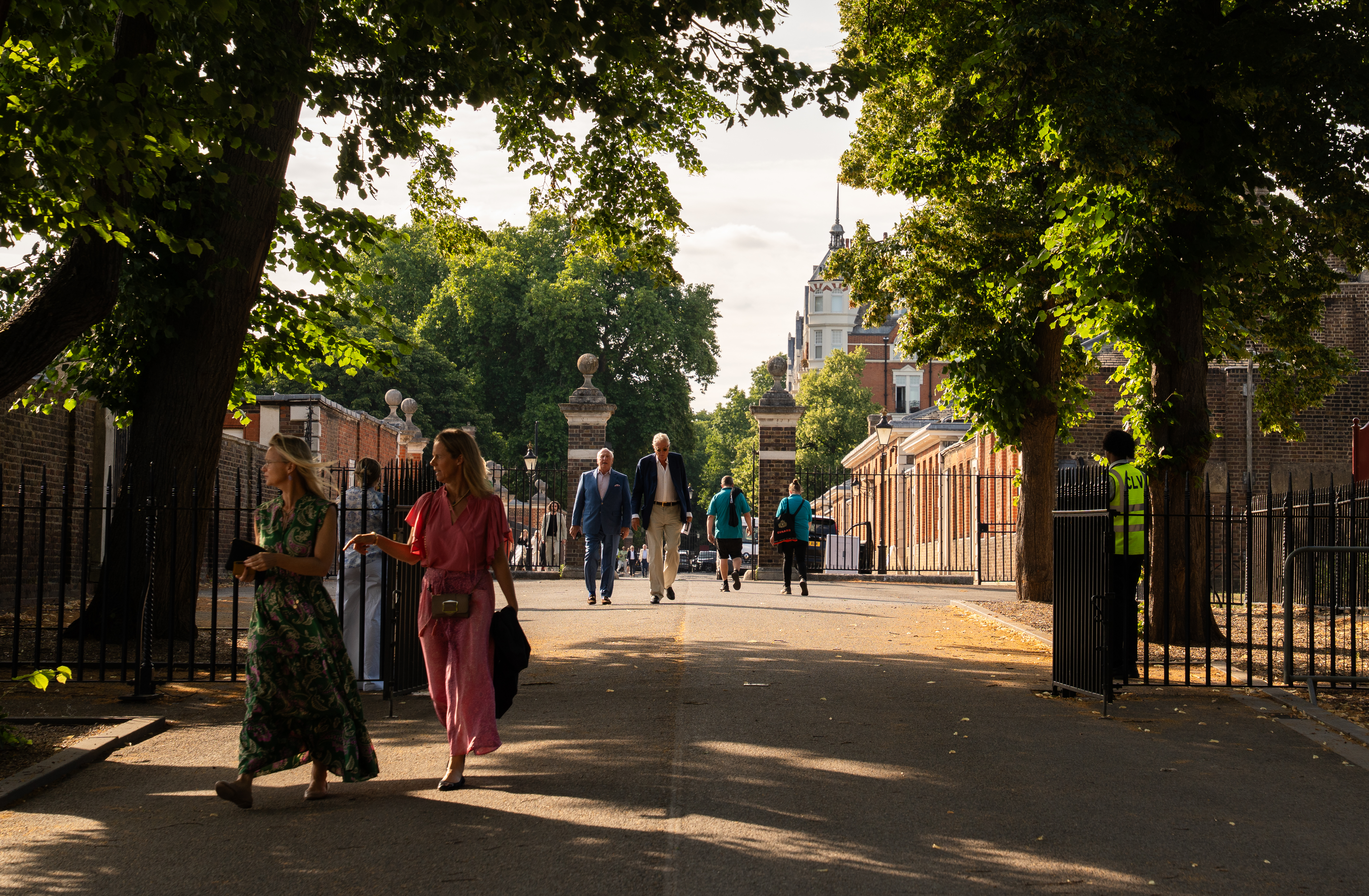 A shot looking through the gates of Royal Hospital Chelsea, where Treasure House Fair takes place. It is a sunny day and people can be seen walking through in smart clothing in groups
