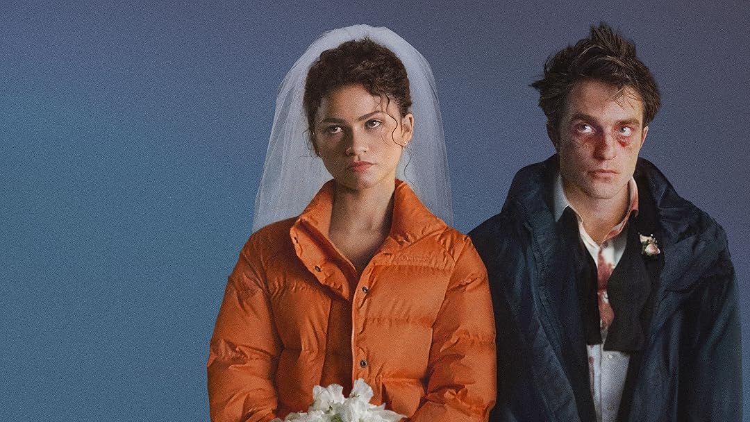 A still from the film "The Drama": A couple sit beside each other, the women to the left wearing an orange coat and wedding veil, the man to the right wearing a black coat