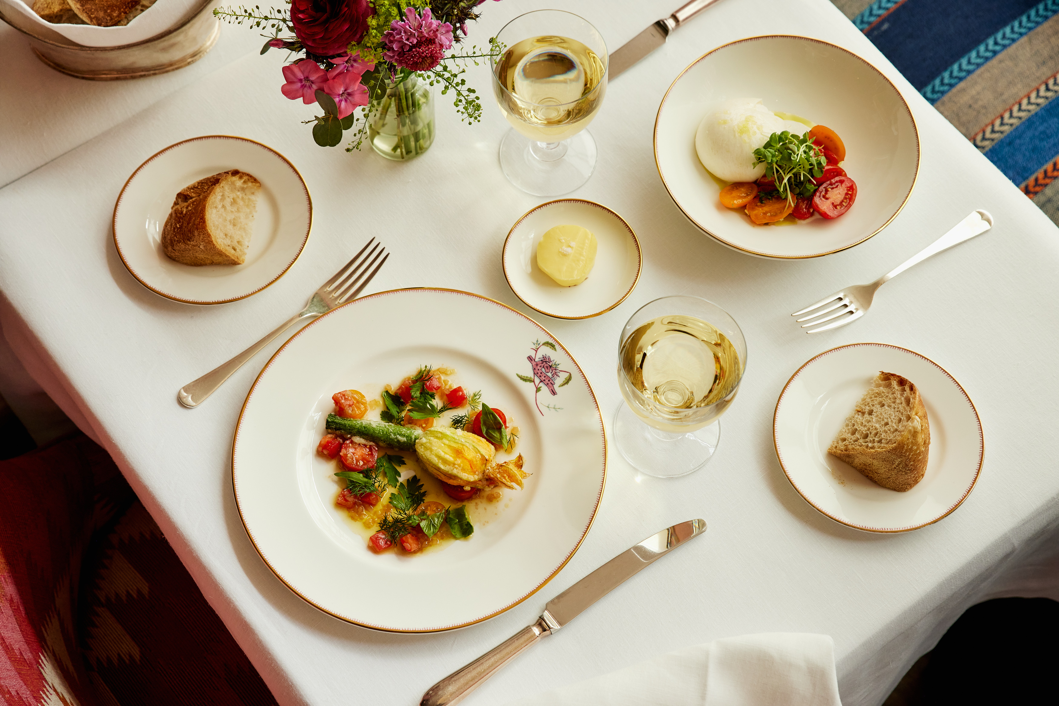 A close-up wide angle shot of a selection of starters from the Summer A La Carte menu at Brumus, including stuffed courgette flower and burrata