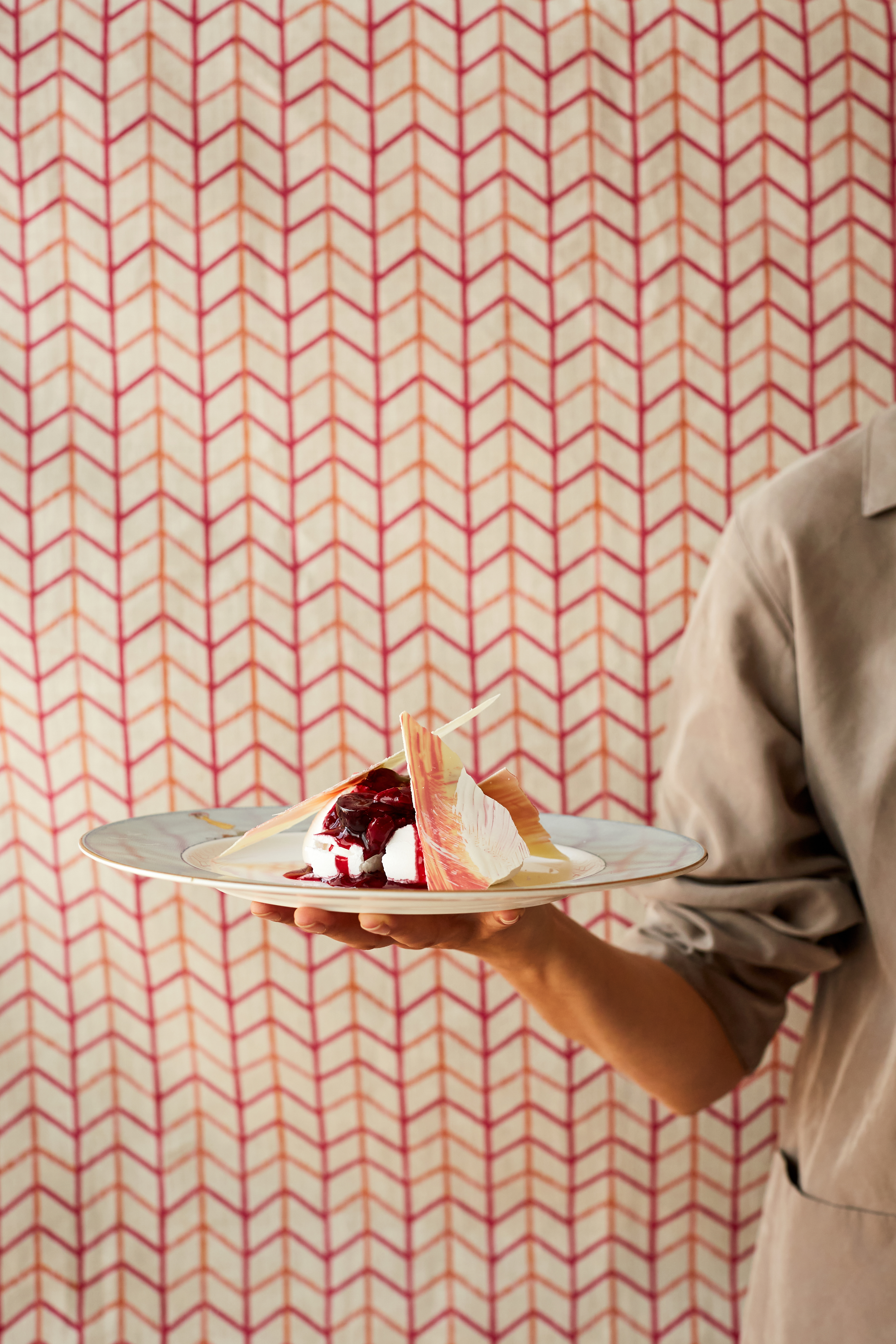 A plate of pavlova being carried by a chef, who is partially in view