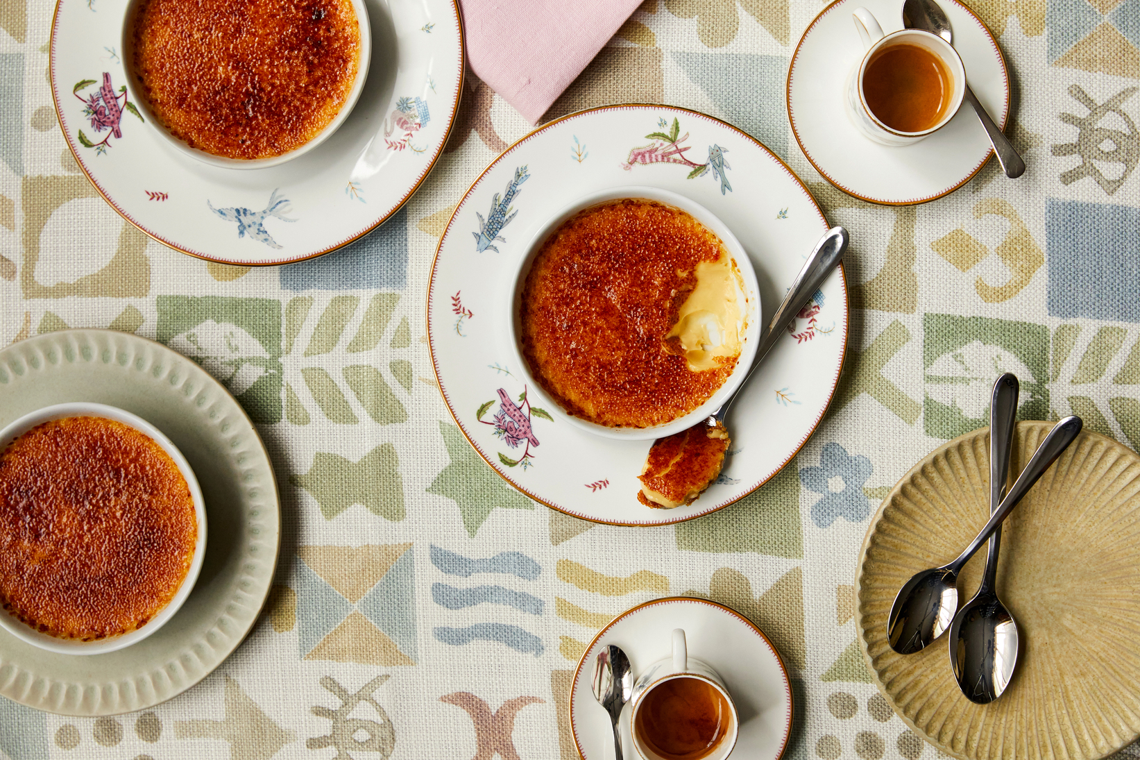 Close up shot of Creme Brulee taken from above, on a tablecloth with a coloured design