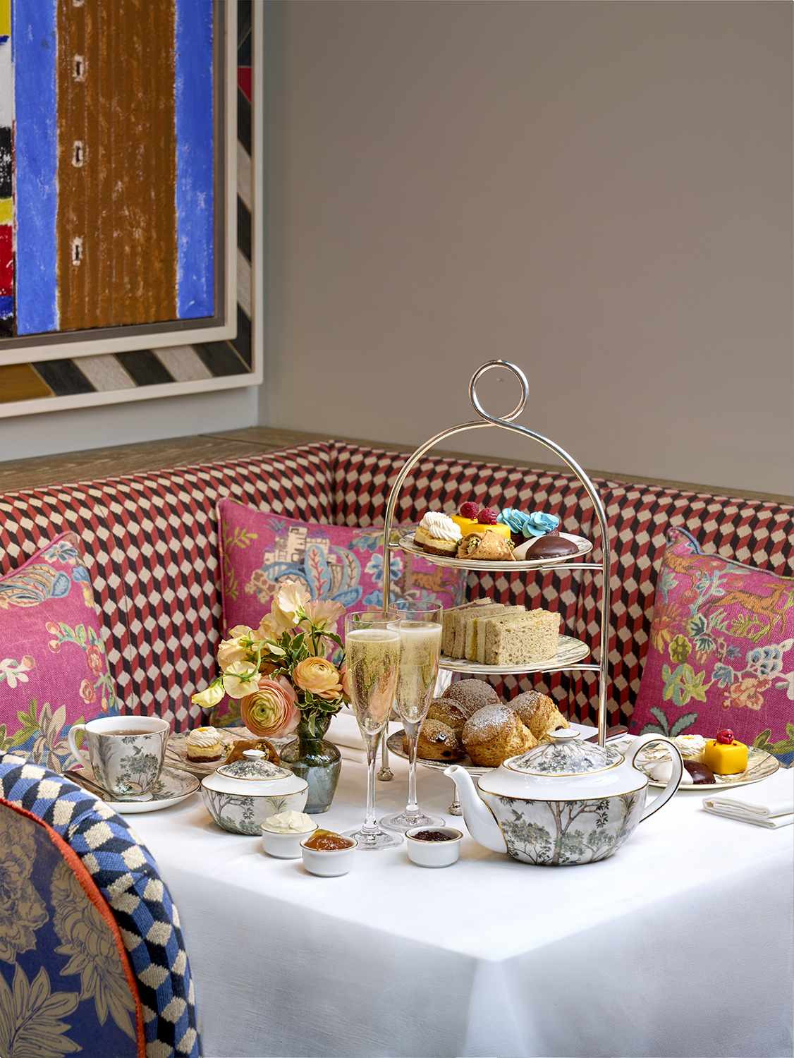 A portrait shot of the New York Afternoon Tea at Warren Street Bar: there is a stand of scones, sandwiches and pastries, served with champagne