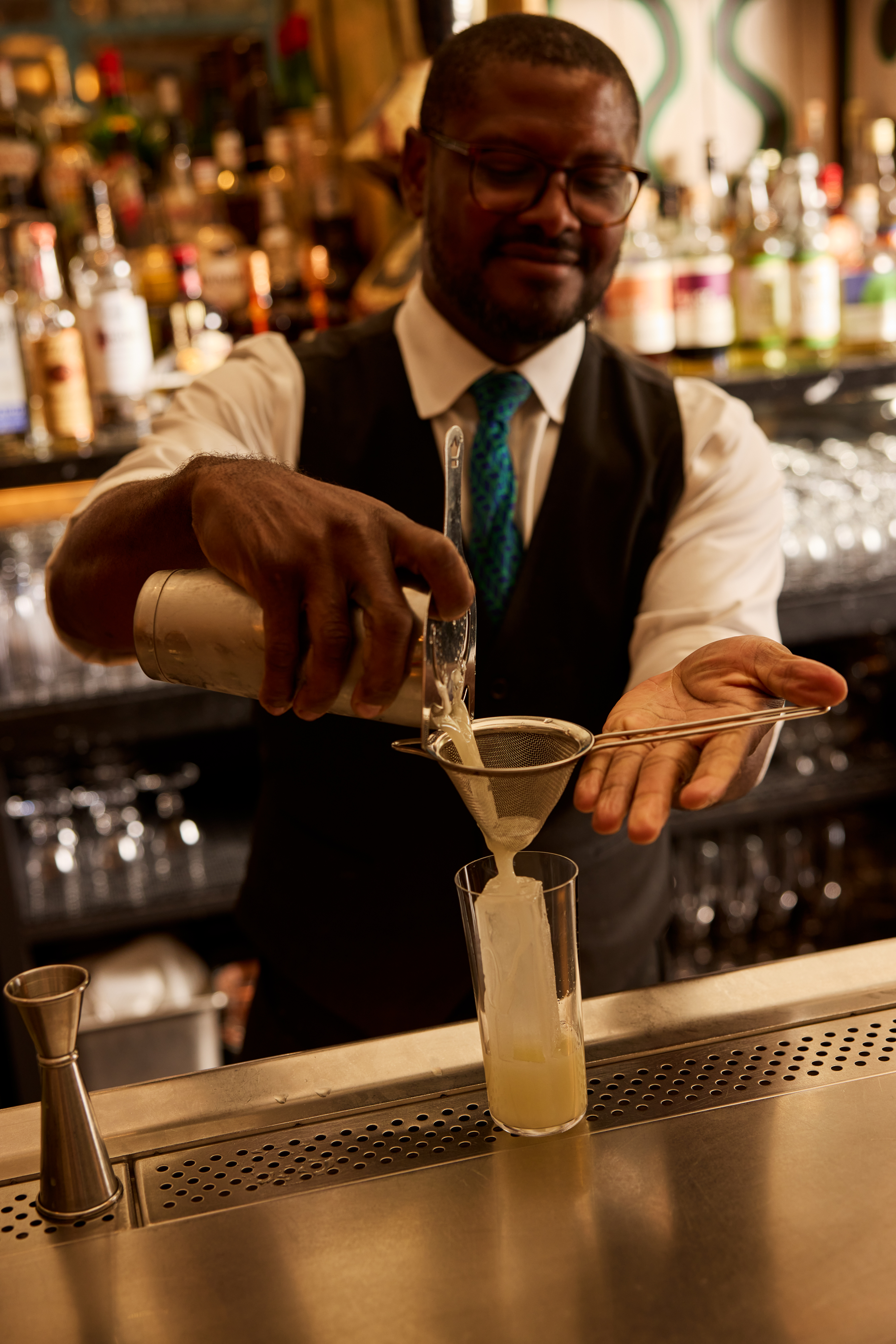 A bartender pours a cocktail through a small sieve into a glass at Warren Street Bar at Warren Street Hotel New York