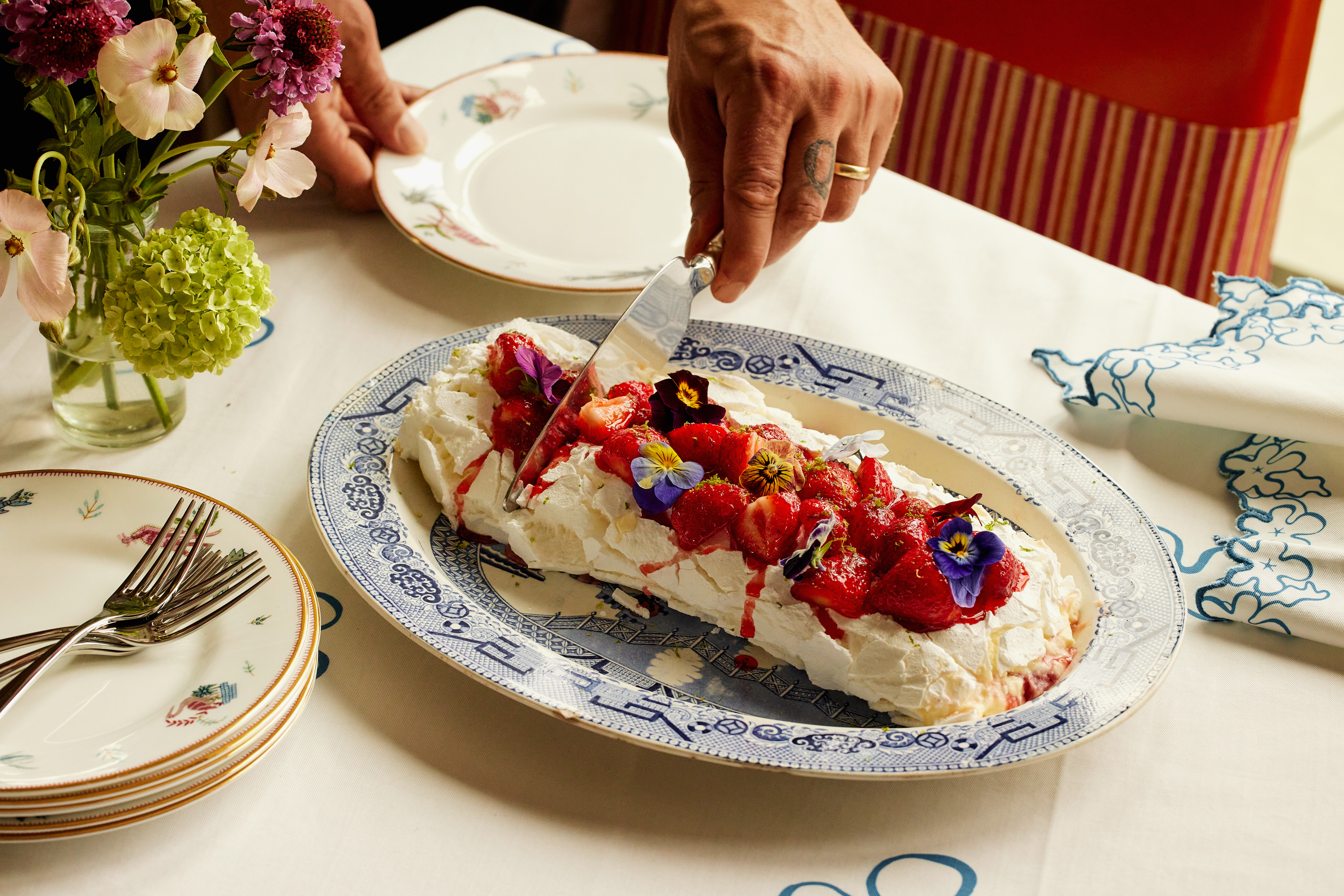 A close-up wide angle shot of the strawberry and lime meringue roulade being served onto a smaller plate