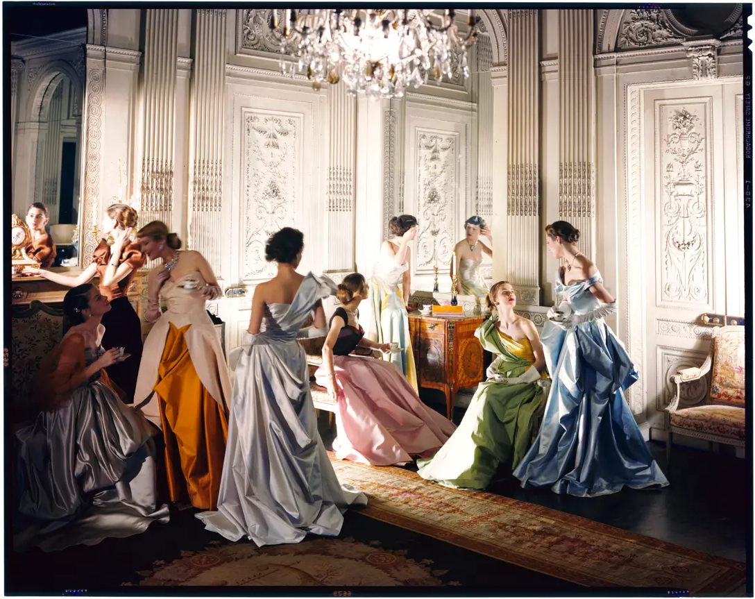 A group of women in coloured evening dresses pose in ballroom