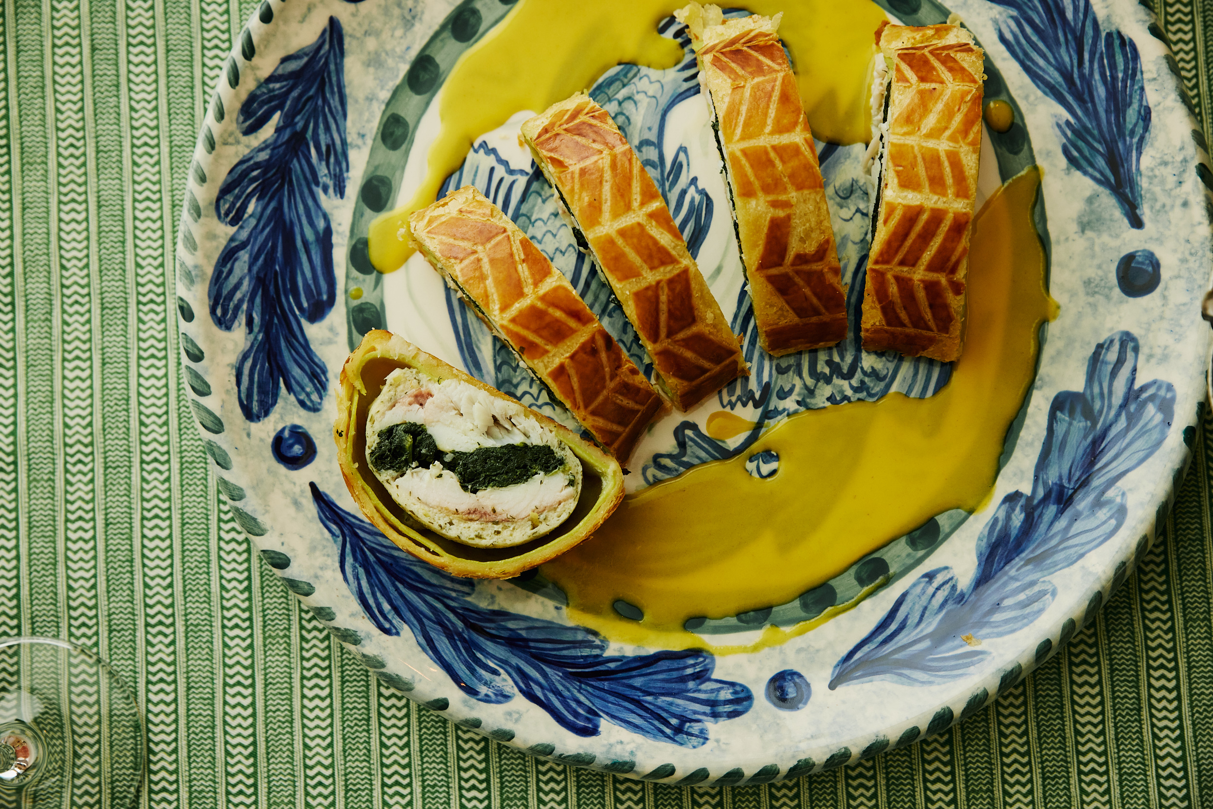 A close up image of the Sea bass en croûte, spinach and Champagne beurre blanc on Sasha Compton crockery to promote the Refuel, Christmas Eve menu at Soho Hotel.