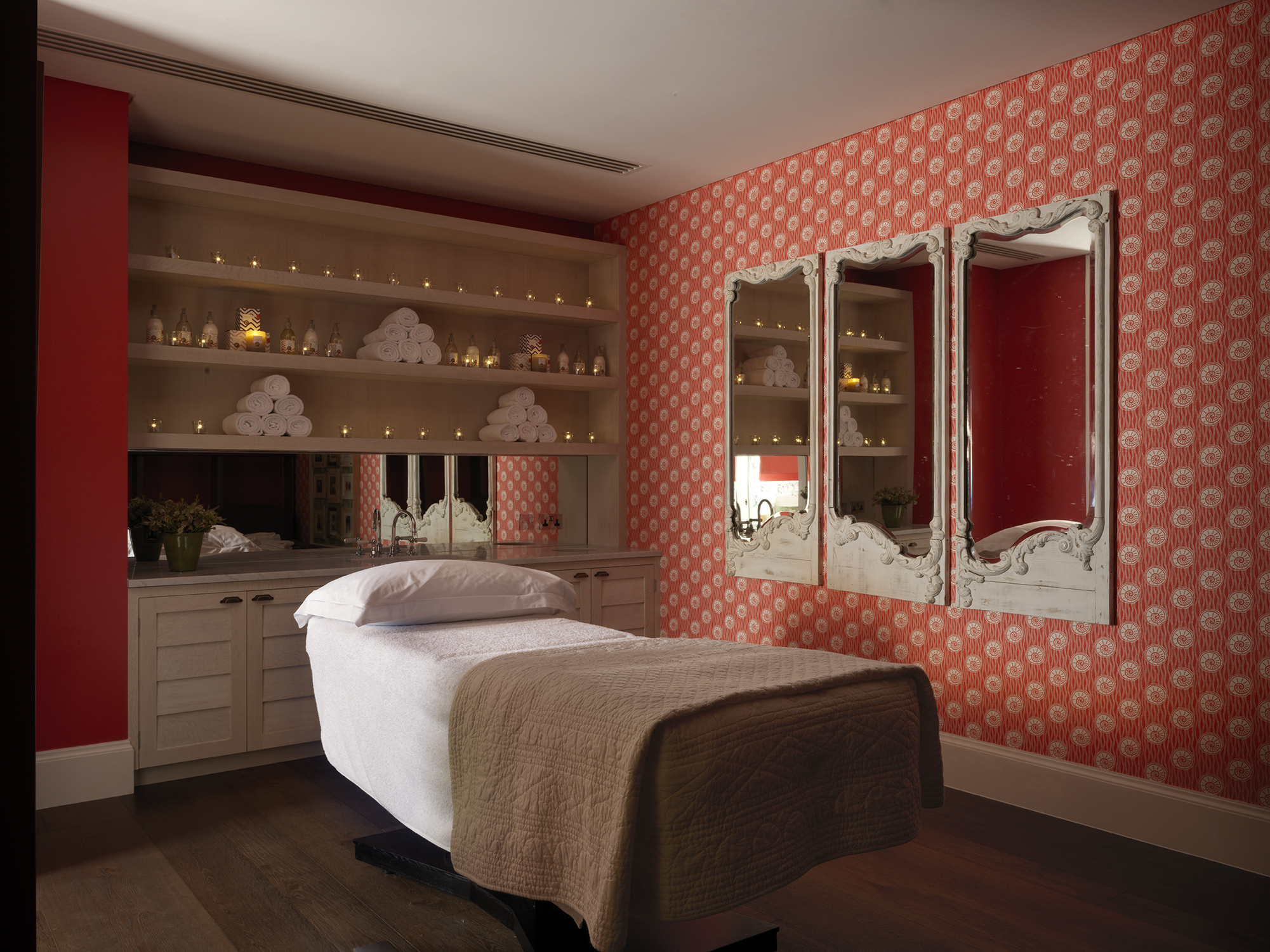 Diagonal shot of a single treatment room, featuring a massage table with fresh white towels, in the Soholistic Spa at Ham Yard Hotel