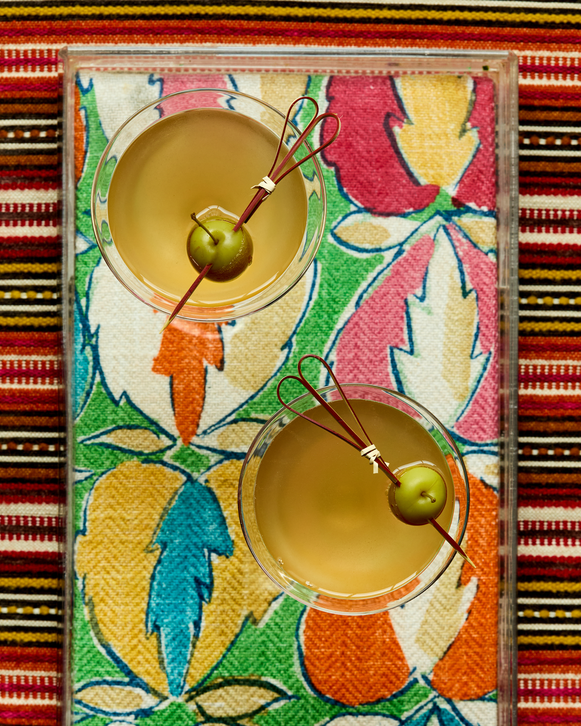 A close up image of two cocktails on a bright colourful tray.