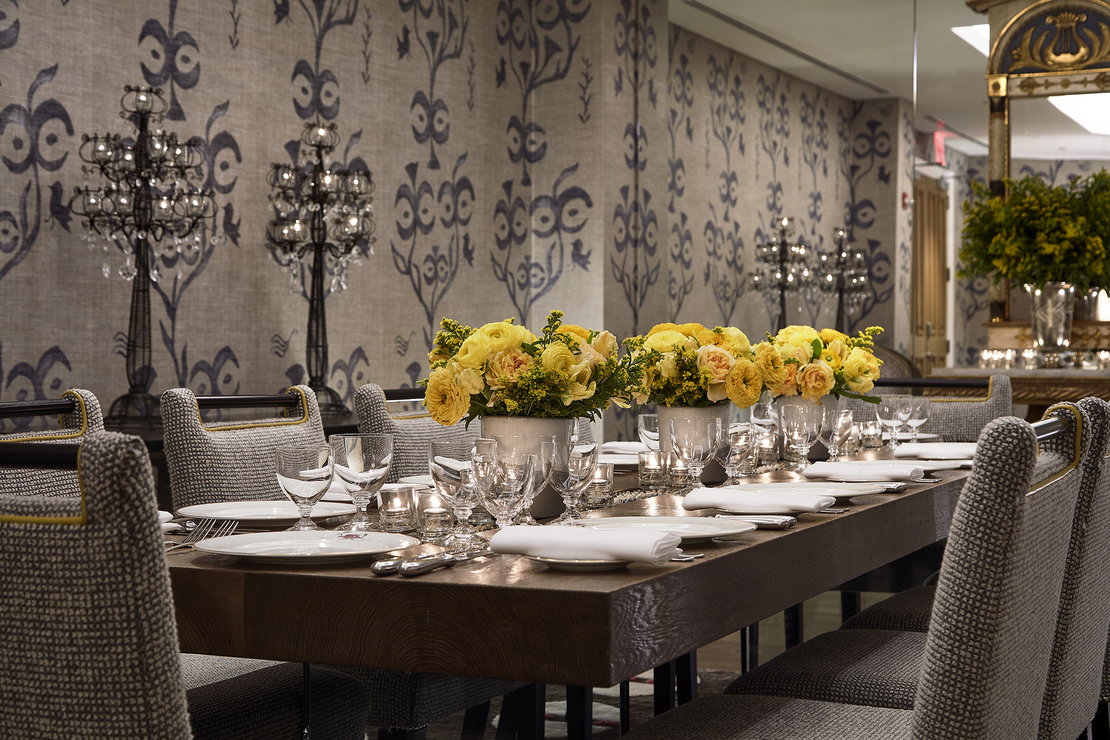 Close shot of a long dining table set-up with dim lighting in the Lafayette private events room at Crosby Street Hotel