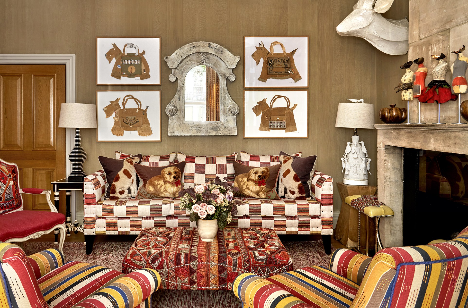 An image focusing on the sofa in the drawing room at Knightsbridge Hotel. In the foreground of the image we see two striped arm chairs facing the center where a fabric embroidered foot stall sits. On the right we see the fireplace, the rooms is all in a autumnal colour scheme.