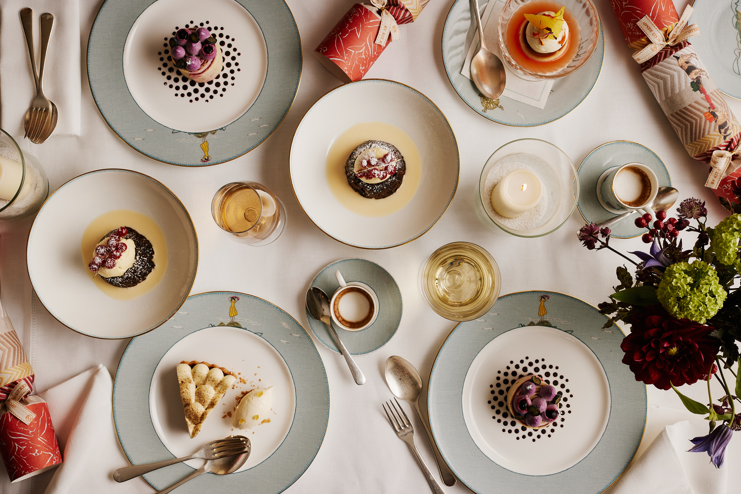 An image from above of the dessert on offer from the Christmas Day menu at Ham Yard restaurant, Ham Yard Hotel. In the image you can see Ham Yard Christmas pudding, brandy sauce and brandy butter, Chestnut and blackberry roulade, Sticky date and Earl Grey tart, bergamot ice cream, Blood orange crème caramel all on Sailors Fairwell crockery.