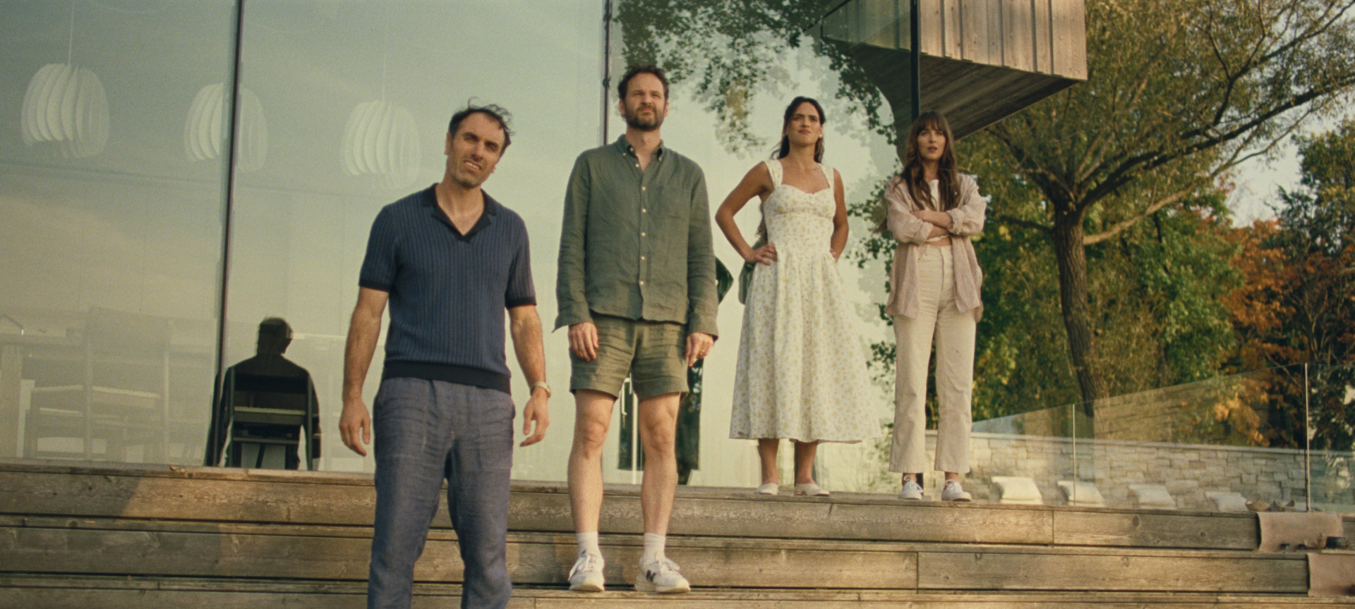 A still from the film "Splitsville": Two men and two women stand on some steps outside a house, looking out